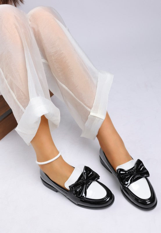 sitting pose showing glossy black and white bow loafers
