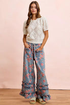 Front view of blue vintage floral wide leg pants with ruffle pocket trim and layered ruffle details.
