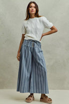 AVAH - model wearing blue and ivory striped wide leg denim pants with a white cable knit sweater and platform slide sandals.