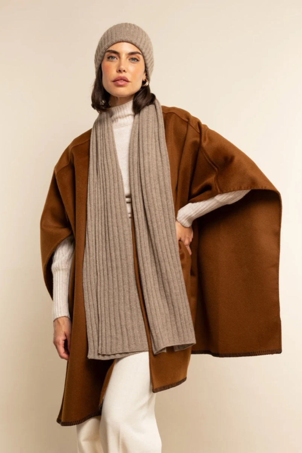Model wearing a long neutral scarf and matching knit beanie
