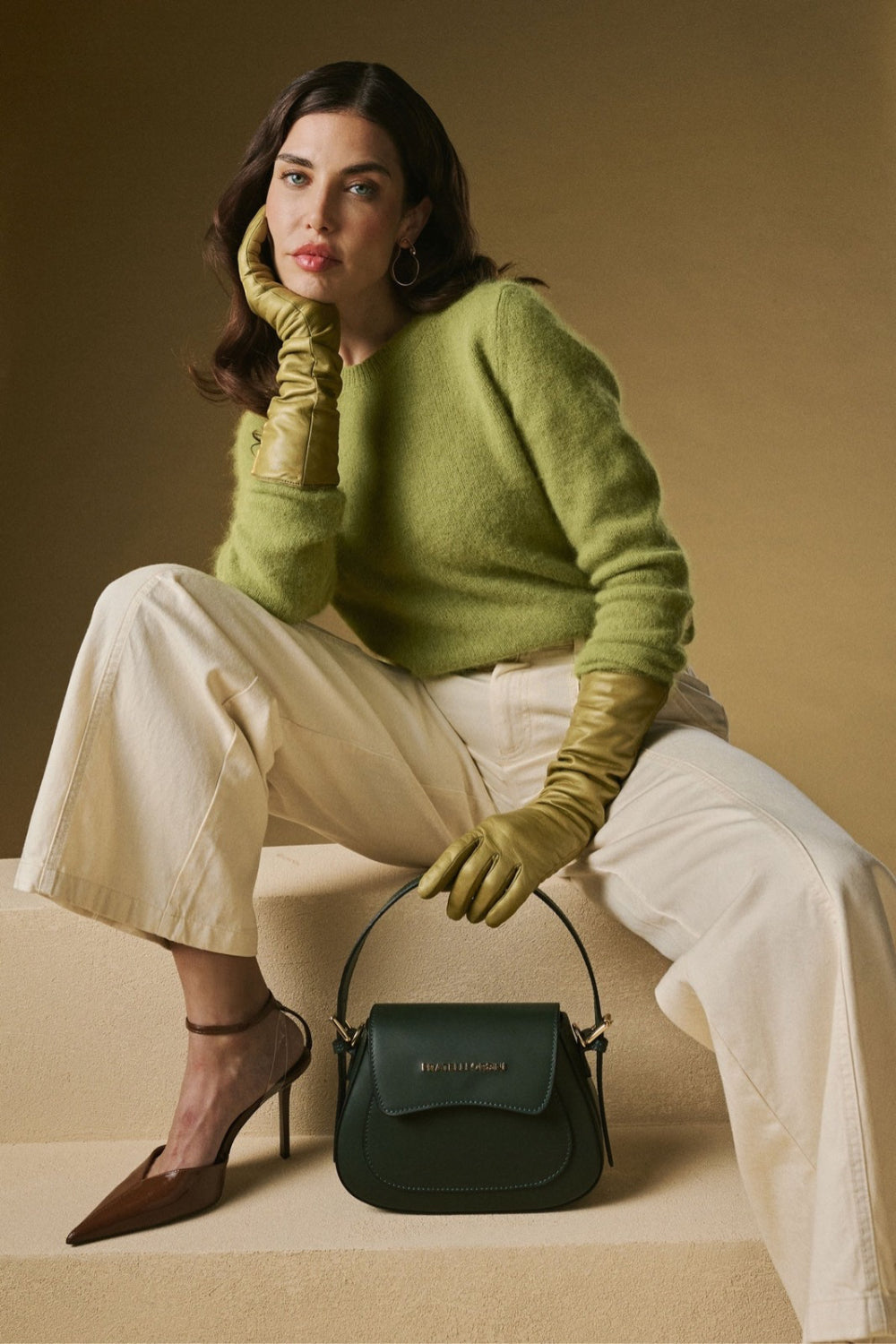Model wearing olive leather gloves with a dark green Fratelli Orsini handbag