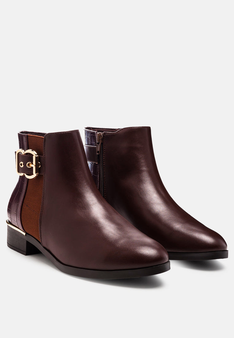 Pair of brown leather ankle boots with a gold buckle on a white background