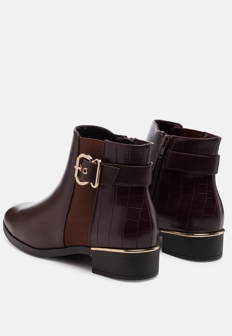 A pair of dark brown ankle boots with a mix of smooth and crocodile-embossed textures, featuring a side buckle strap and low block heels.