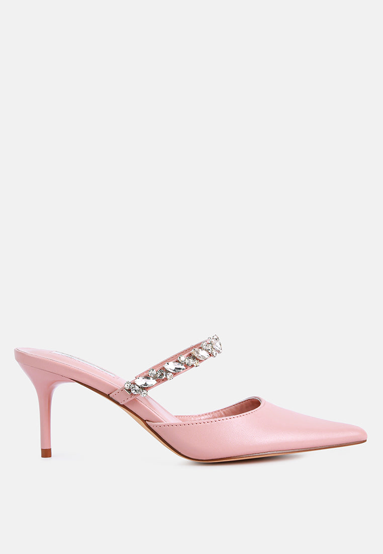 Pink mid-heeled shoe with a decorative diamante strap across the top on a light blue background, side view