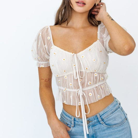 Avah Couture- Easy to throw on, this cute top is your new go-to! Perfect for a spring picnic with friends or a lunch date. This semi-sheer top features a delicate embroidered daisy flower, puff sleeves, and tie detail at the front. Pair it with jeans, shorts, or your favorite trouser pants.  Embroidery Floral Sheer Sweetheart neckline Short sleeve Puff sleeve Ruched Tie detail Cropped length- Ivory Yellow Floral