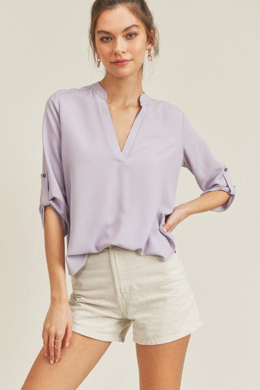 A chic, casual and stylish top. The simple v neck and high low hem add a trendy touch to this top. Wear it with jeans or skirt for a fall casual look or dress it up for work by pairing it with a pencil skirt or slacks. This v neck top is the ultimate staple piece in any wardrobe. Features v neckline, high low hem and roll up button quarter sleeve.  V-neckline Avah Couture