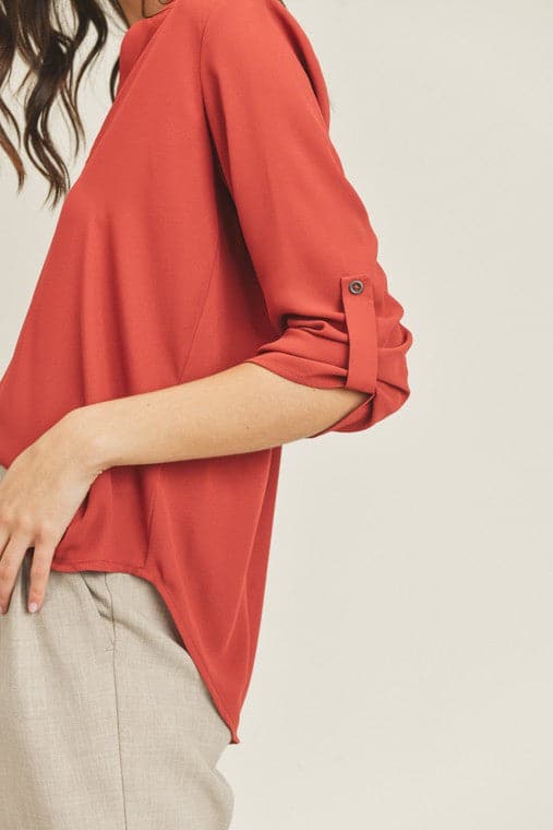 A chic, casual and stylish top. The simple v neck and high low hem add a trendy touch to this top. Wear it with jeans or skirt for a fall casual look or dress it up for work by pairing it with a pencil skirt or slacks. This v neck top is the ultimate staple piece in any wardrobe. Features v neckline, high low hem and roll up button quarter sleeve.  V-neckline Avah Couture