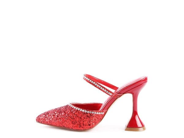 The perfect pair of red glitter mules with rhinestone embellishment, designed to make you shine. Featuring a sculpted heel, pointed toe and crystal decorated elastic strap. Avah Couture