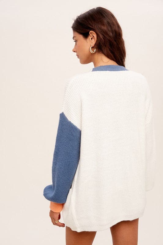 Our Color Block Sweater is a fall favorite, designed with you in mind. This sweater is a stylish addition to any wardrobe. Featuring a low v neckline with button closure, long sleeves with ribbed contrast color band and pouch pockets at bottom front. It’s finished with a clean weaved hem for an elegant look that can take you from day to night in comfort. Avah Couture