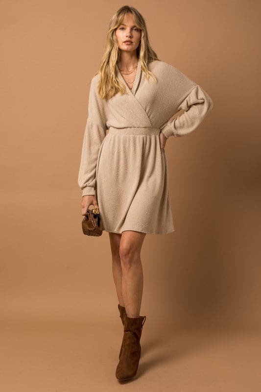 An on trend look that is both stylish and comfortable, this long sleeve dress is sure to have you looking your best! This sweater dress features a surplice neckline, long sleeves with band cuff and a chic dropped shoulder. The perfect short dress that can be worn from day to night. Avah Couture