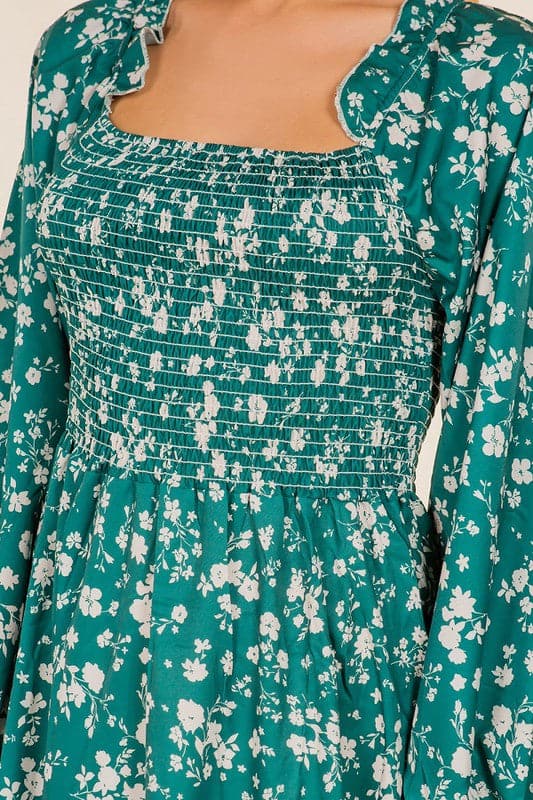 Be the flower girl in this darling full length dress. Made from a lovely floral print fabric and features a sweet square neckline and long sleeve design. This long sleeved, smocked dress has a flattering A line shape that flatters any figure. Accessorize with some cute ankle boots or strappy stilettos for a stylish look this season. Avah Couture