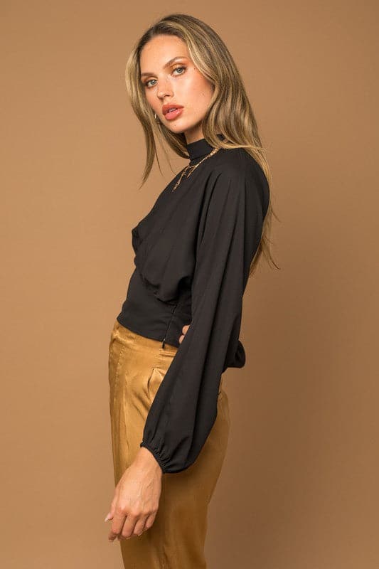 This black top is the quintessential piece for any fashion savvy closet. The chic top features a mock neck, dramatic dolman long sleeves, fitted bottom and double button keyhole back. Wear with your favorite jeans or vegan leather pants for the perfect everyday look. Avah Couture