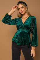 This wrap front velvet top is perfect for your next holiday party. This long sleeve top features a wrap front with waist tie that is sure to add some style to your look! Avah Couture