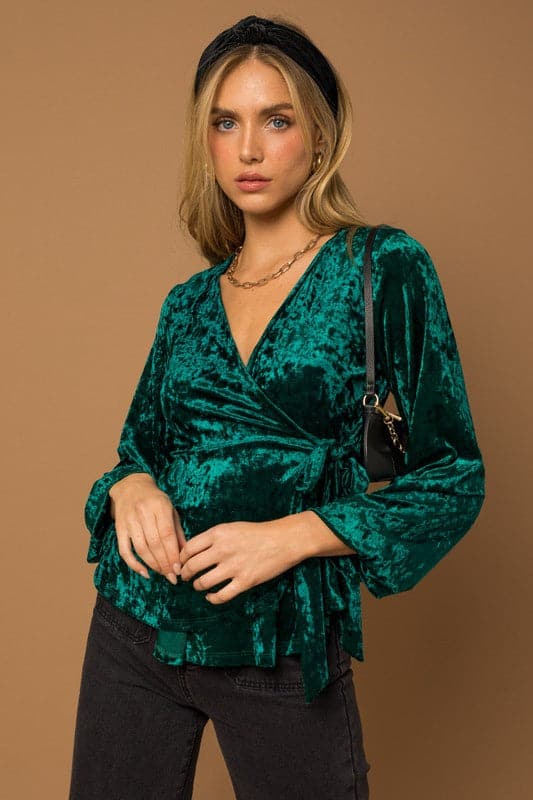 This wrap front velvet top is perfect for your next holiday party. This long sleeve top features a wrap front with waist tie that is sure to add some style to your look! Avah Couture