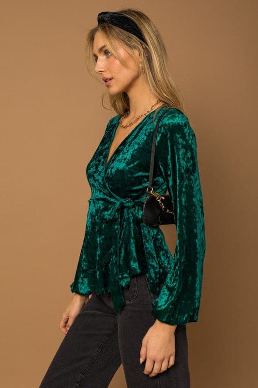 This wrap front velvet top is perfect for your next holiday party. This long sleeve top features a wrap front with waist tie that is sure to add some style to your look! Avah Couture