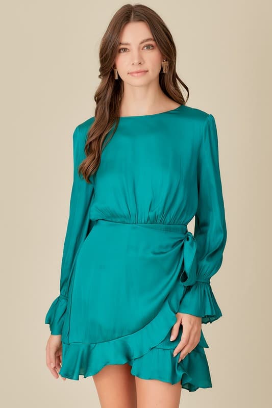 This woven dress is a must have for any woman who loves to look stylish. It features a long sleeve, a belled cuff, back zipper closure, an open back with tie detail, ruffle detail and tie waist styling. Dress it up with strappy heels and jewelry or wear it casually with flats. Avah Couture
