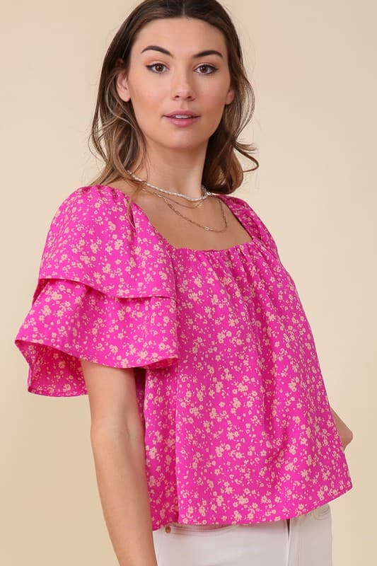 Avah Couture- Make a sweet impression in this smocked square neck blouse covered in delightful blooms. This fuchsia floral top has a self-tie open back and short sleeves accented with ruffles. Embrace the phenomenal florals of spring.  Floral print Smocked square neck Ruffle short sleeves Open back with self-tie Short length- Fuchsia Pink 