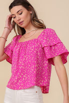 Avah Couture- Make a sweet impression in this smocked square neck blouse covered in delightful blooms. This fuchsia floral top has a self-tie open back and short sleeves accented with ruffles. Embrace the phenomenal florals of spring.  Floral print Smocked square neck Ruffle short sleeves Open back with self-tie Short length- Fuchsia Pink 