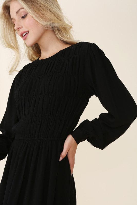 This beautiful midi dresses has four tiers of elastic bands at the bodice which creates a lovely ruched effect. This design gives it an elegant and feminine appearance. The All Dressed Up Ruched Midi Dress has a boat neckline, long sleeves with button at each cuff and below the knee length for easy transition into fall. Wear it with heels and a clutch bag for a chic look. This dress is lined.  