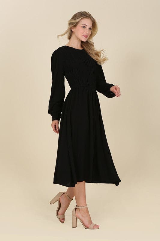 This beautiful midi dresses has four tiers of elastic bands at the bodice which creates a lovely ruched effect. This design gives it an elegant and feminine appearance. The All Dressed Up Ruched Midi Dress has a boat neckline, long sleeves with button at each cuff and below the knee length for easy transition into fall. Wear it with heels and a clutch bag for a chic look. This dress is lined.  