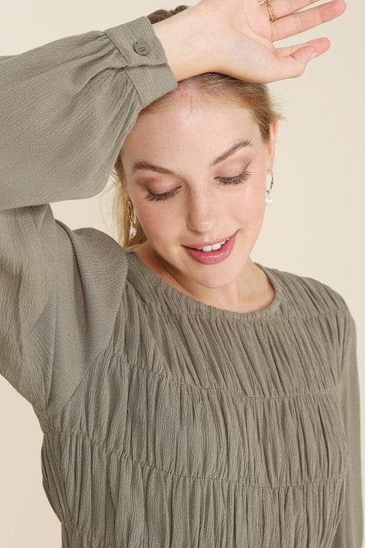 This beautiful midi dresses has four tiers of elastic bands at the bodice which creates a lovely ruched effect. This design gives it an elegant and feminine appearance. The All Dressed Up Ruched Midi Dress has a boat neckline, long sleeves with button at each cuff and below the knee length for easy transition into fall. Wear it with heels and a clutch bag for a chic look. This dress is lined.  
