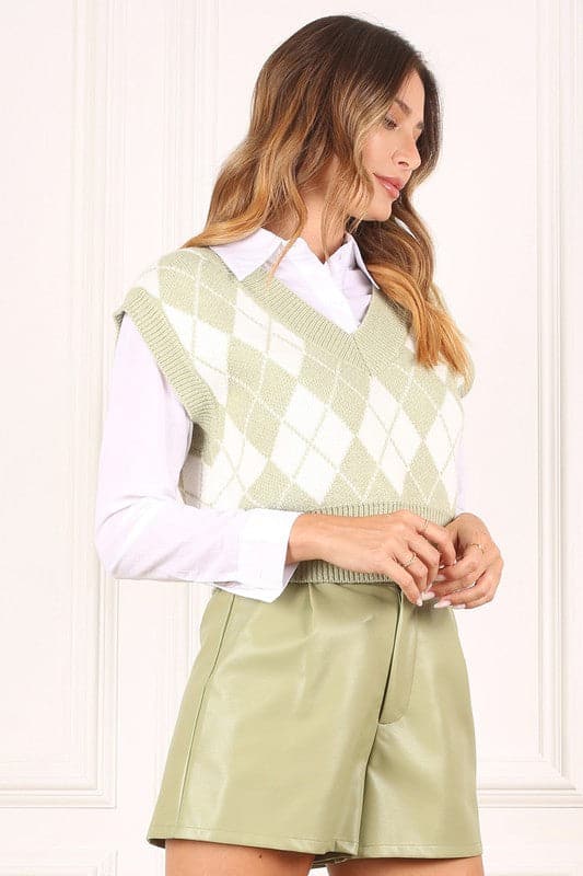 A knitted vest is a must have for fall and winter, and this version features an argyle pattern and V neckline to add some interest. It's sleeveless so you can wear it alone or layered over a button down shirt or tank. Green color. Avah Couture