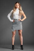 A skirt that turns heads everywhere. Our fashion-forward houndstooth shirred wrap skirt combines a modern angle with a classic twist that has set a benchmark in skirts. The shirred front detail creates an overlapping effect, and the asymmetrical hem gives it extra allure! Comes in black and white or Ivory. Avah Couture