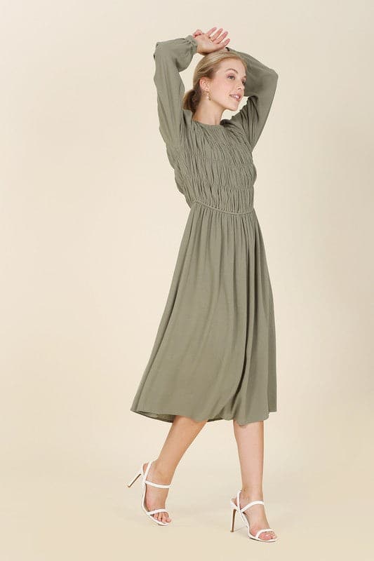 This beautiful midi dresses has four tiers of elastic bands at the bodice which creates a lovely ruched effect. This design gives it an elegant and feminine appearance. The All Dressed Up Ruched Midi Dress has a boat neckline, long sleeves with button at each cuff and below the knee length for easy transition into fall. Wear it with heels and a clutch bag for a chic look. This dress is lined.  