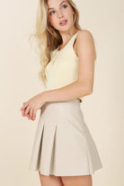 Alexis Pleated Vegan Leather Mini Skirt - Ivory. This vegan leather pleated mini skirt is made of high quality faux leather. The skirt has four pin tucks for each front and back and a side zipper closure. The Alexis Pleated Vegan Mini Skirt will make your legs look longer and slimmer and pairs perfectly with a blouse for work or play! 