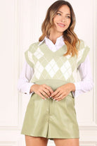 A knitted vest is a must have for fall and winter, and this version features an argyle pattern and V neckline to add some interest. It's sleeveless so you can wear it alone or layered over a button down shirt or tank. Green color. Avah Couture